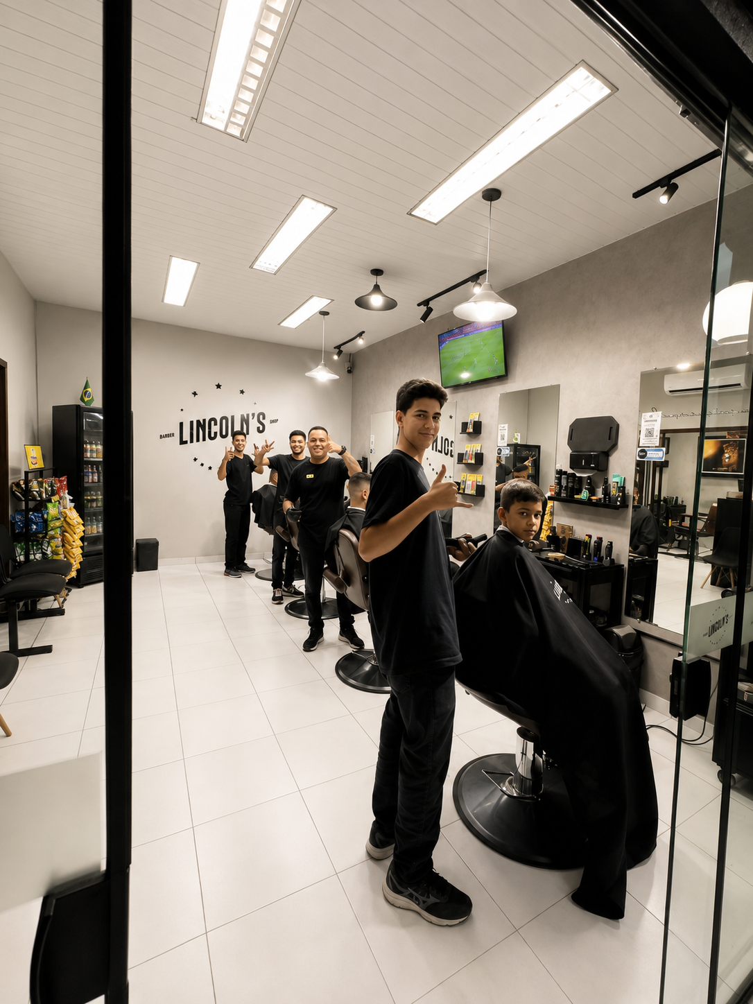 Interior da Lincoln's Barbershop com o time trabalhando e o letreiro da marca na parede